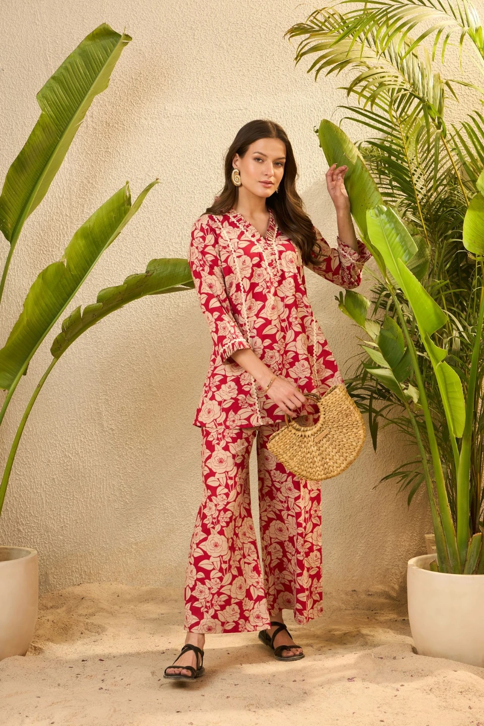 Woman in floral outfit holding straw bag near plants